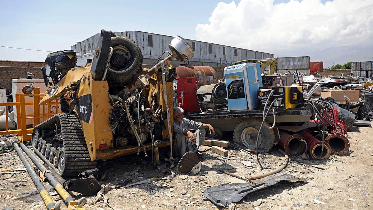 FILE - In this May 3, 2021 file photo, a man rests in the shade of destroyed machinery sold by the US military to a scrapyard, outside Bagram Air Base, in Afghanistan. In 2001 the armies of the world united behind America and Bagram Air Base, barely an hours drive from the Afghan capital Kabul, was chosen as the epicenter of Operation Enduring Freedom, as the assault on the Taliban rulers was dubbed. It’s now nearly 20 years later and the last US soldier is soon to depart the base. (AP Photo/Rahmat Gul, File)