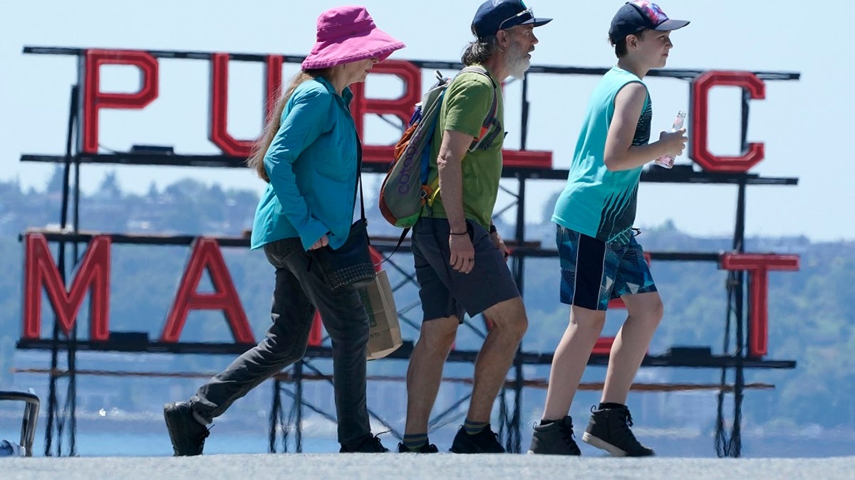 People walk near Pike Place Market, Tuesday, June 29, 2021, in Seattle. The unprecedented Northwest U.S. heat wave that slammed Seattle and Portland, Oregon, moved inland Tuesday — prompting an electrical utility in Spokane, Washington, to resume rolling blackouts amid heavy power demand. (AP Photo/Ted S. Warren)