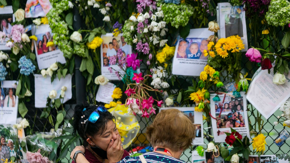 Mourners visit the makeshift memorial near the site of the collapsed condominium in Surfside, Fla., on Tuesday. (AP/Miami Herald)