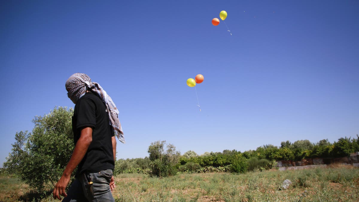Masked Palestinian man walks away after launching incendiary balloons towards Israel. (Ahmed Zakot / SOPA Images/Sipa USA)(Sipa via AP Images)