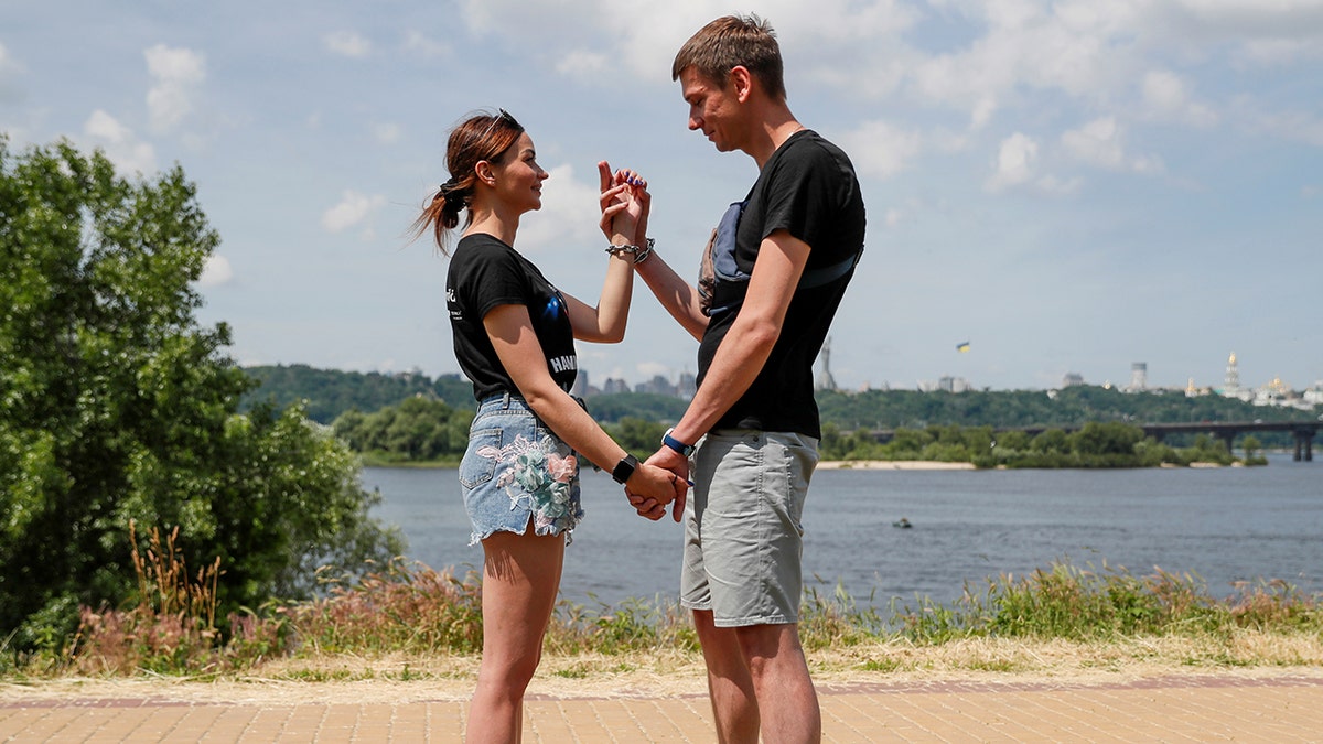 Alexandr Kudlay and Viktoria Pustovitova, who handcuffed themselves and spent 123 days together, wait before having the chain dismantled in Kyiv, Ukraine June 17, 2021. The Ukrainian couple split up after 123 days handcuffed together, shedding their bonds on national TV and saying the experiment had brought home uncomfortable truths. (REUTERS/Gleb Garanich)