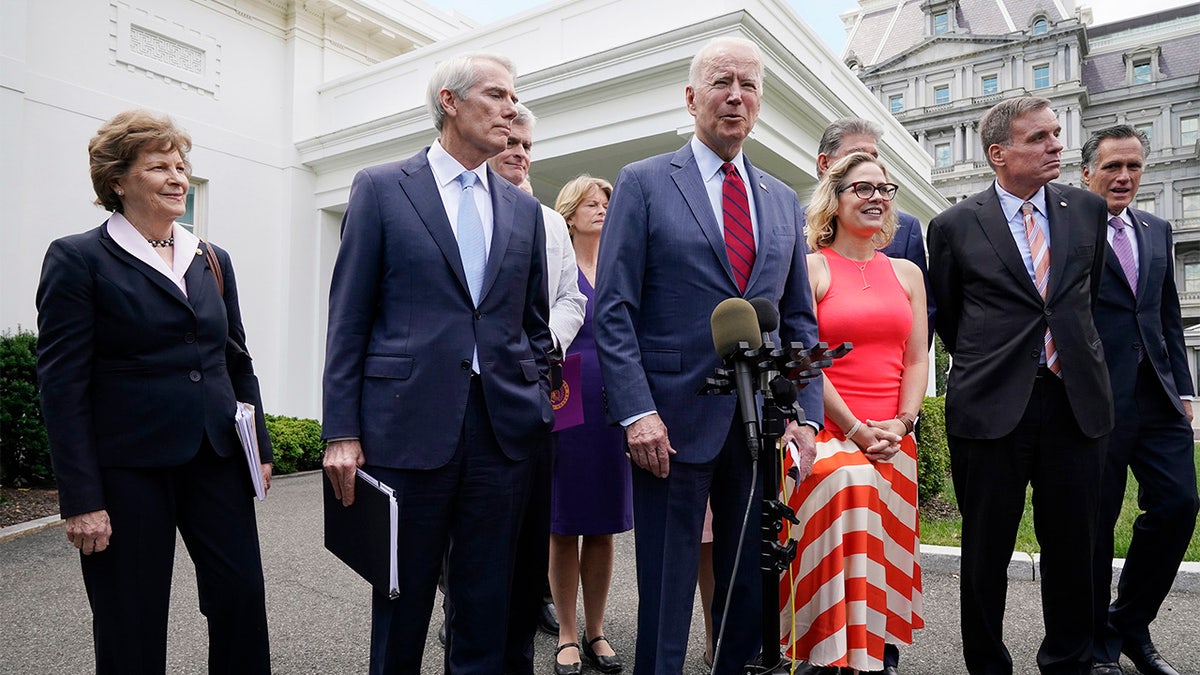 President Joe Biden, with a bipartisan group of senators, speaks Thursday June 24, 2021, outside the White House in Washington. Biden invited members of the group of 21 Republican and Democratic senators to discuss the infrastructure plan. From left are, Sen. Jeanne Shaheen, D-N.H., Sen. Rob Portman, R-Ohio, Sen. Bill Cassidy, R-La., Sen. Lisa Murkowski, R-Alaska, Biden, Sen, Joe Manchin, D-W.Va., Sen. Kyrsten Sinema, D-Ariz, Sen. Mark Warner, D-Va., and Sen. Mitt Romney, R-Utah.  (AP Photo/Jacquelyn Martin)