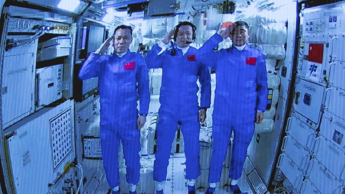 Chinese astronauts salute after successfully entering the Tianhe space station module as they are displayed on a big screen at the Beijing Aerospace Control Center in Beijing, on Thursday, June 17, 2021. (Jin Liwang/Xinhua via AP)