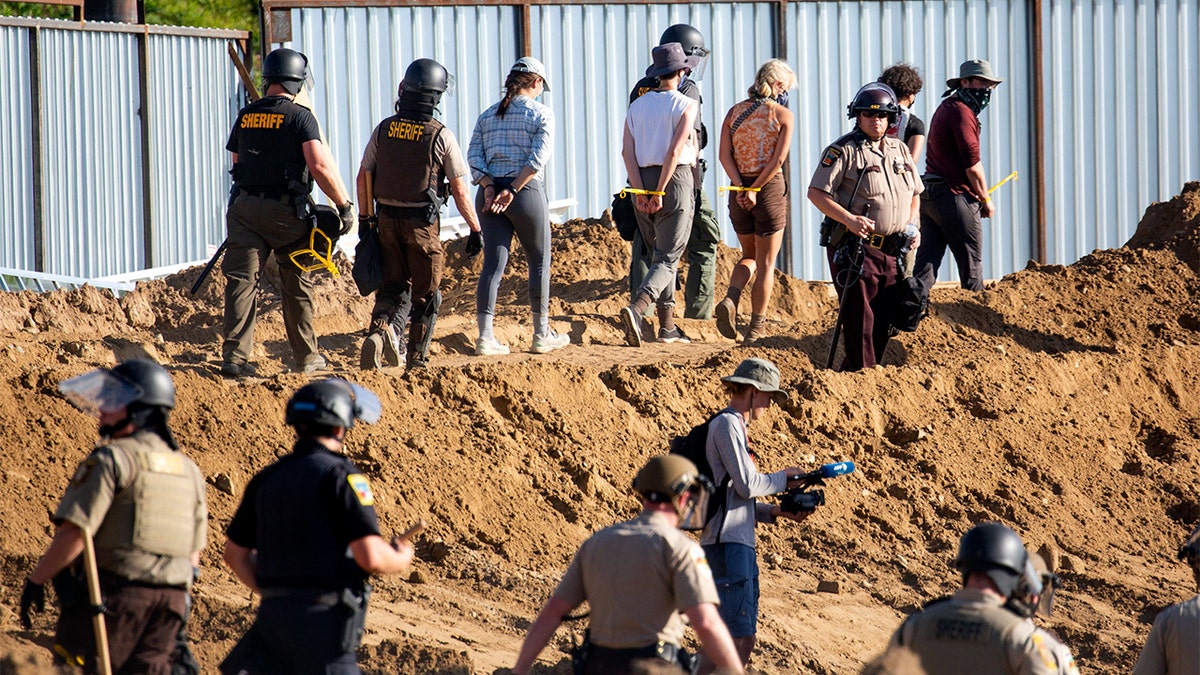 FILE - In this June 7, 2021, file photo, activists are walked through an Enbridge Line 3 pump station after being arrested near Park Rapids, Minn. Members of the Rise Coalition, an Indigenous-led environmental organization, and allies erected a prayer camp on June 7 at the Enbridge construction site along the Mississippi River near Solway. They and other Line 3 opponents had marched to the area with hundreds of others protesting the pipeline before pitching their camp at the end of a wooden boardwalk leading to the site. (Evan Frost/Minnesota Public Radio via AP, File)