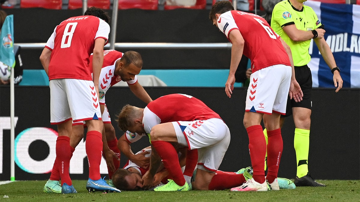 Denmark players help Denmark's midfielder Christian Eriksen after he collapsed before the medics arrive during the UEFA EURO 2020 Group B football match between Denmark and Finland at the Parken Stadium in Copenhagen on June 12, 2021. (JONATHAN NACKSTRAND/AFP via Getty Images)