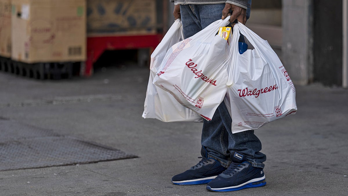 A person holds Walgreens shopping bags in front of a store in San Francisco, California, U.S., on Tuesday, April 13, 2021. Walgreens Boots Alliance Inc. is scheduled to release earnings figures on April 15.