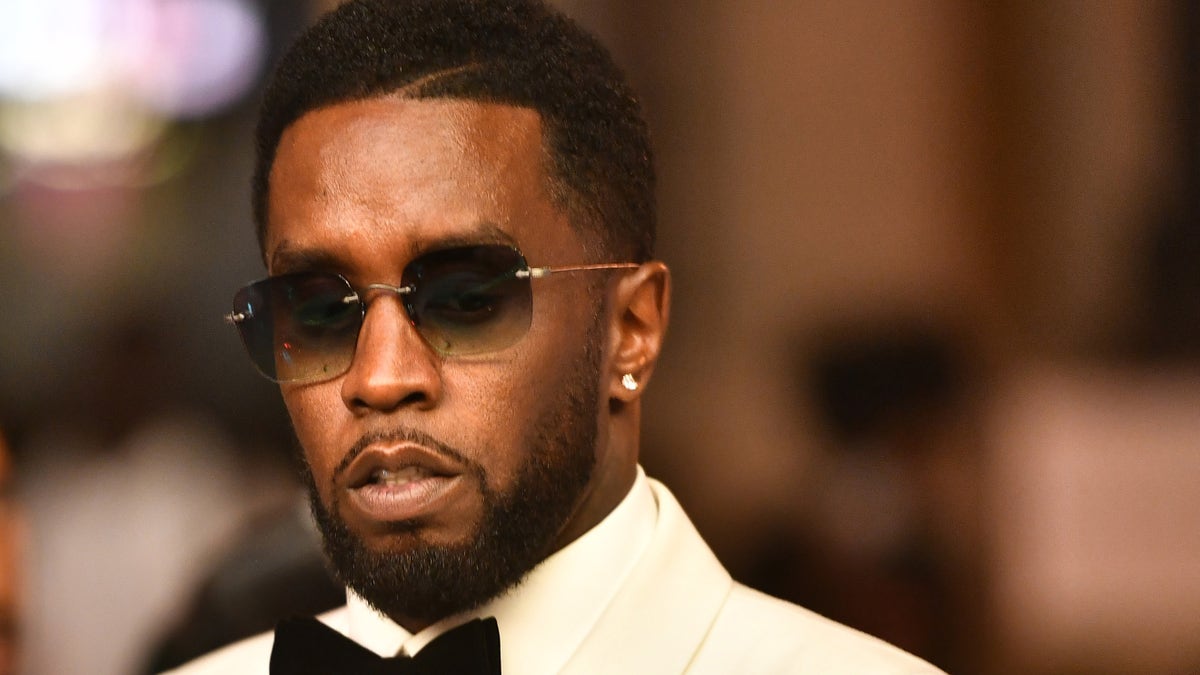 Sean Diddy Combs wears a white tuxedo and black bow tie.