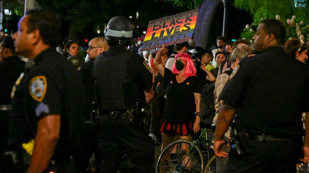 A person holds a pride colored "black lives matter" sign near NYPD in riot gear during pride celebrations in Washington Square Park on June 27, 2021 in New York City. (Photo by Alexi Rosenfeld/Getty Images)