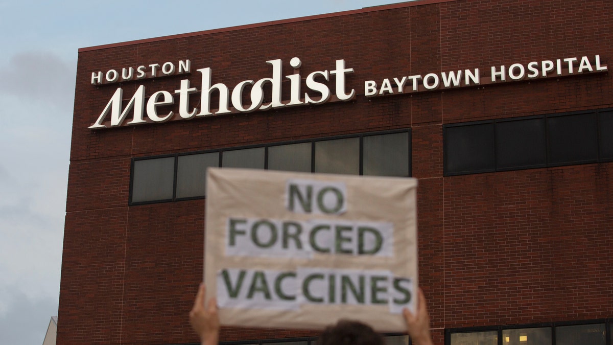 FILE - In this June 7, 2021, file photo, a person holds a sign to protest at Houston Methodist Hospital in Baytown, Texas, a policy that says hospital employees must get vaccinated against COVID-19 or lose their jobs. June 22, 2021. (Yi-Chin Lee/Houston Chronicle via AP, File)