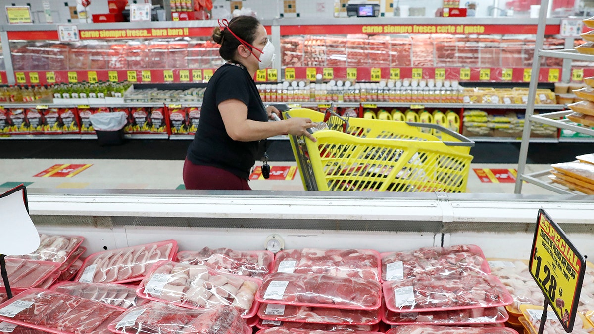 In this April 29, 2020, file photo, a shopper wears a mask as she walks through the meat products at a grocery store in Dallas. 