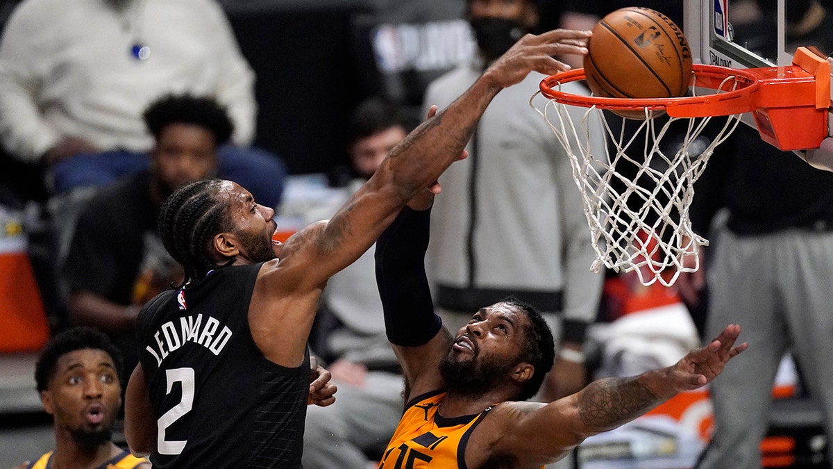 Los Angeles Clippers forward Kawhi Leonard, center, dunks over Utah Jazz center Derrick Favors, right, during the first half in Game 4 of a second-round NBA basketball playoff series Monday, June 14, 2021, in Los Angeles. (AP Photo/Mark J. Terrill)