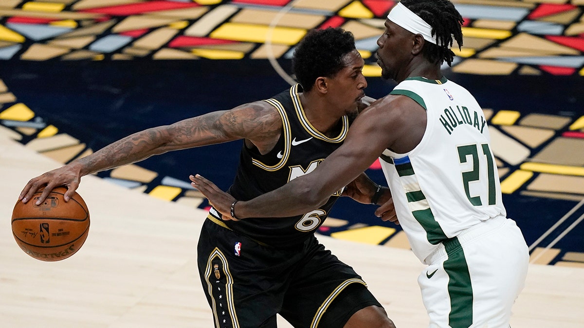 Atlanta Hawks' Lou Williams (6) keeps the ball away from Milwaukee Bucks' Jrue Holiday (21) during the first half of Game 4 of the NBA basketball Eastern Conference finals Tuesday, June 29, 2021, in Atlanta. (AP Photo/Brynn Anderson)