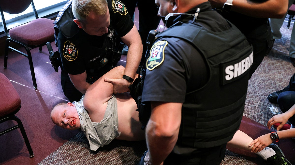 A man is detained after a fight broke out during a Loudoun County School Board meeting which included a discussion of Critical Race Theory and transgender students, in Ashburn, Virginia, on June 22, 2021.
