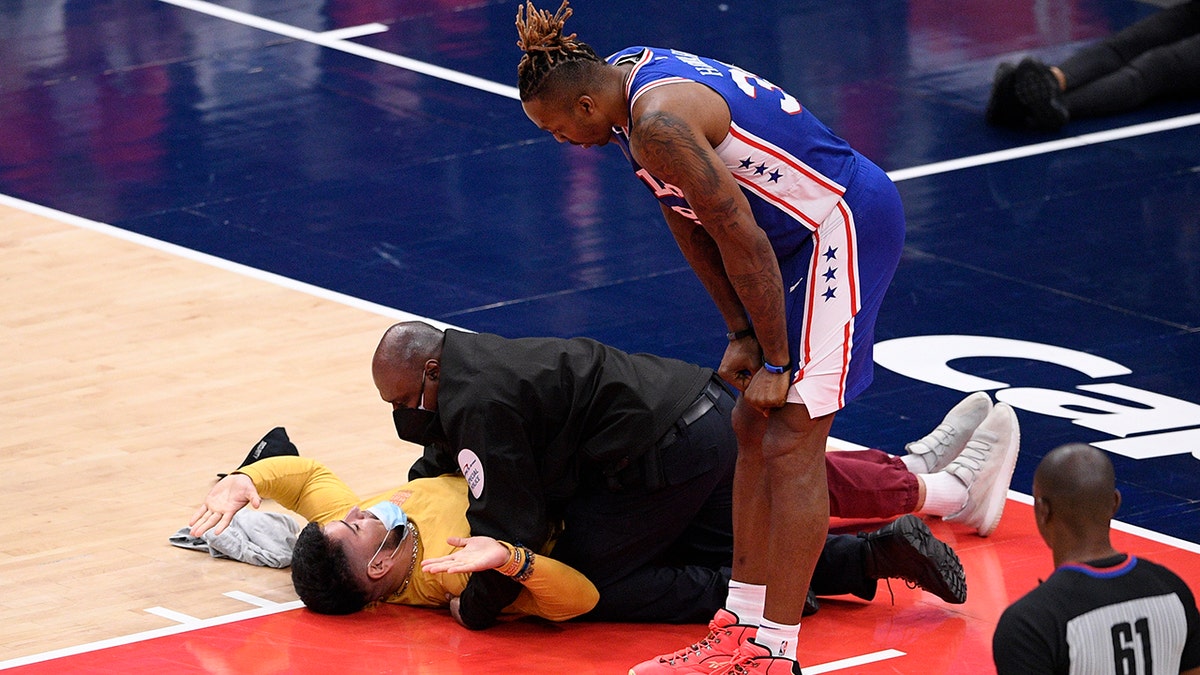 Philadelphia 76ers center Dwight Howard (39) watches as a fan who ran onto the court is restrained by security personnel during the second half of Game 4 in a first-round NBA basketball playoff series against the Washington Wizards, Monday, May 31, 2021, in Washington. (AP Photo/Nick Wass)