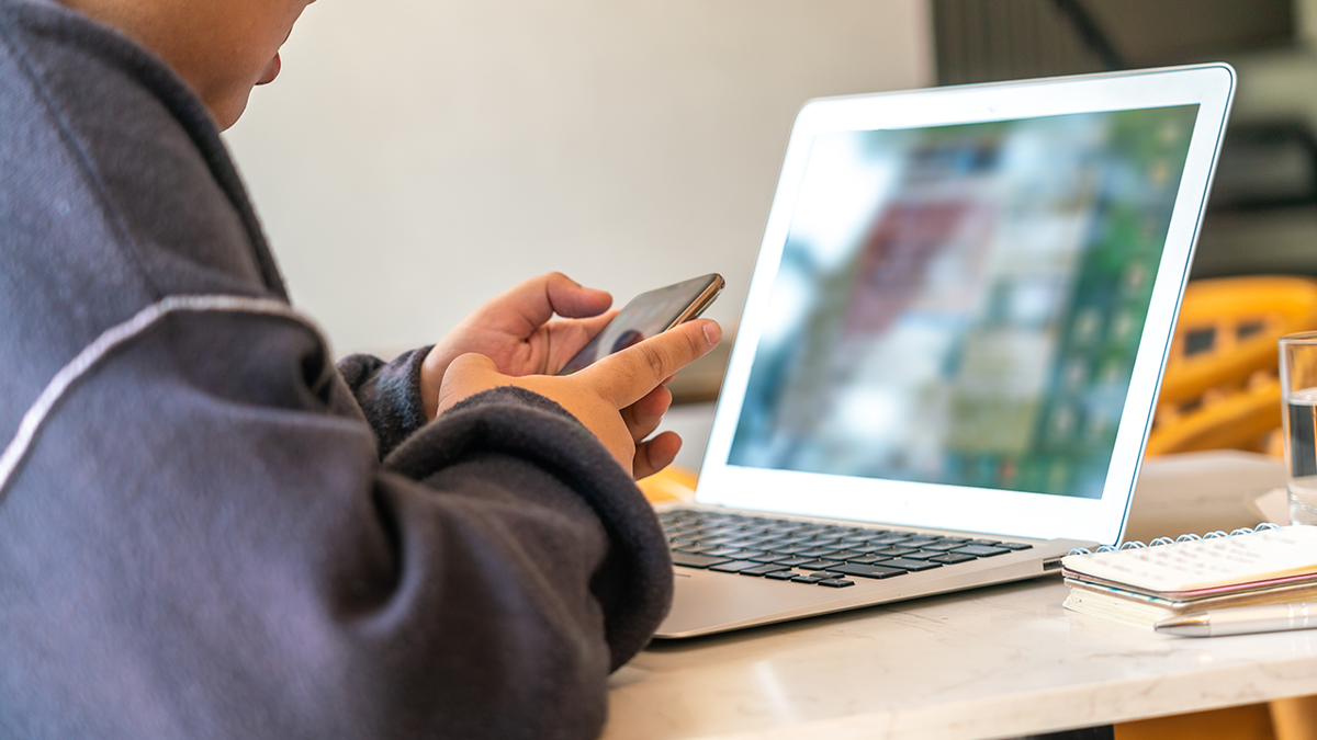 child on iPhone in front of computer