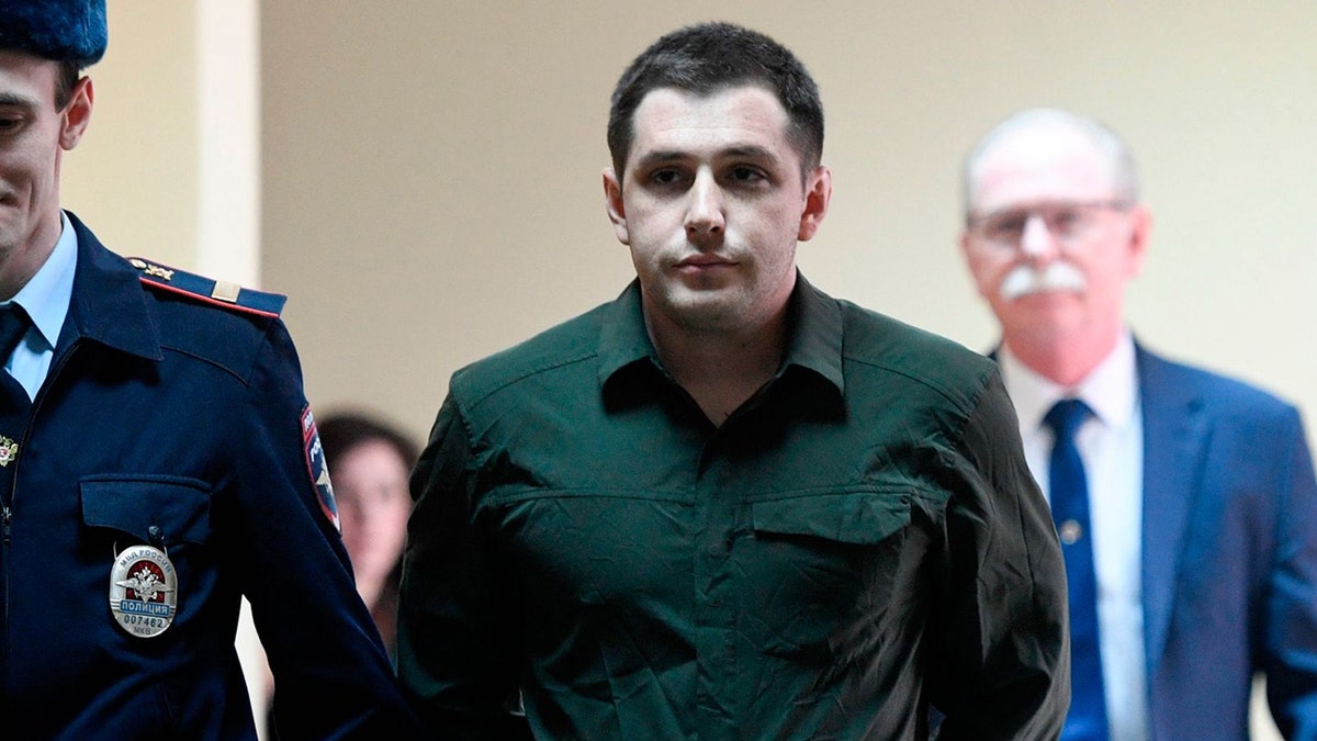 Police officers escort former U.S. Marine Trevor Reed, charged with attacking police, into a courtroom prior to a hearing in Moscow on March 11, 2020.