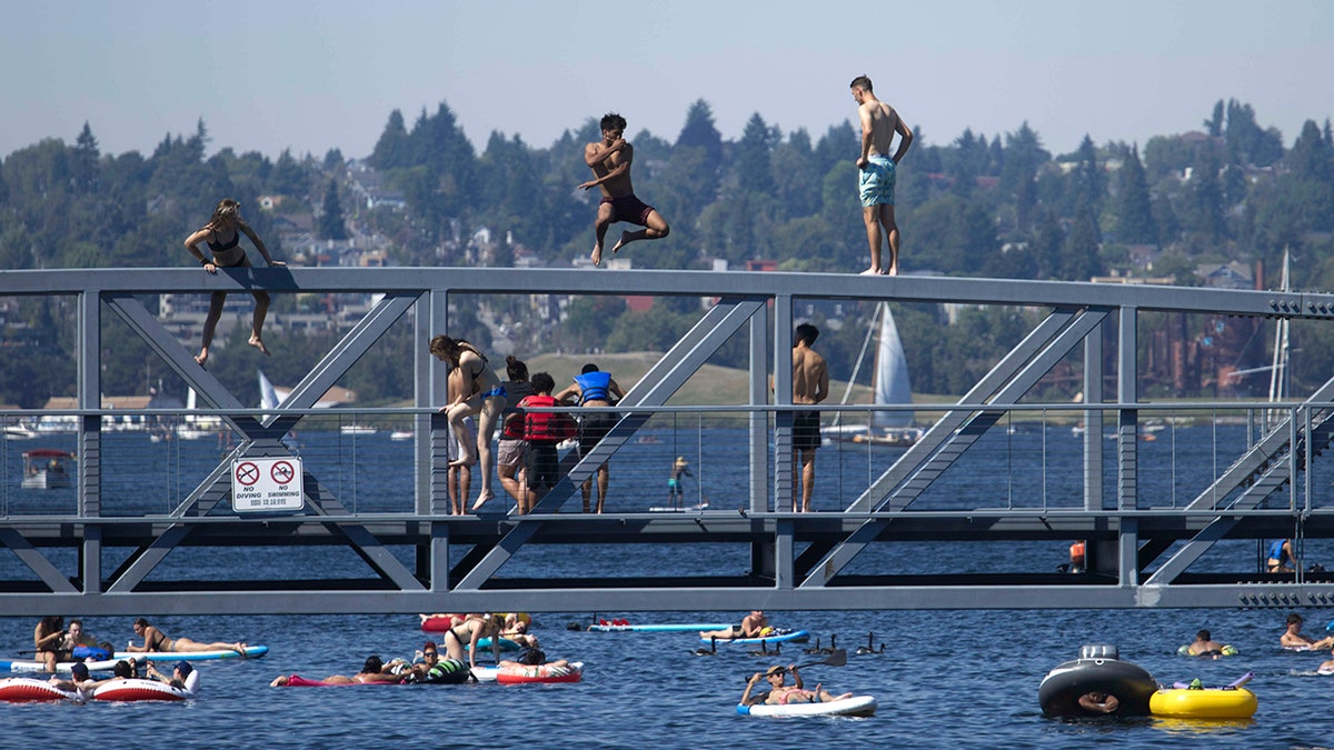 Two people jump from a pedestrian bridge at Lake Union Park into the water during a heat wave hitting the Pacific Northwest, Sunday, June 27, 2021, in Seattle. A day earlier, a record high was set for the day with more record highs expected today and Monday. (AP Photo/John Froschauer)
