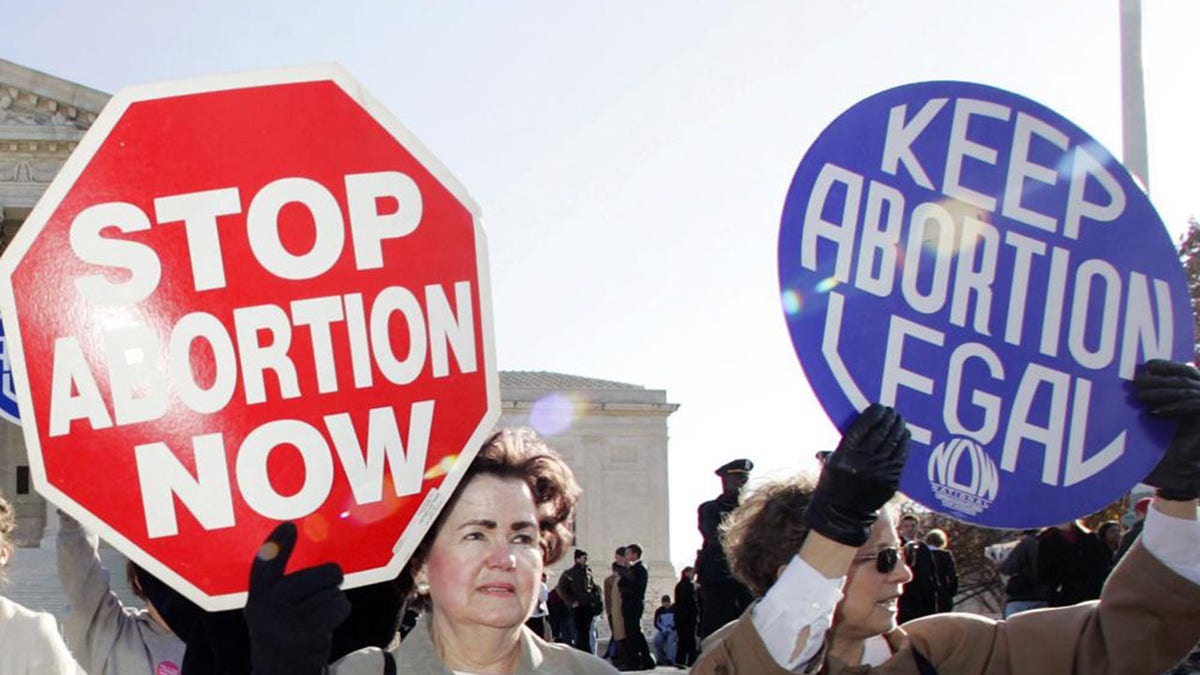 FILE - In this Nov. 30, 2005 file photo, an anti-abortion supporter stands next to a pro-choice demonstrator outside the U.S. Supreme Court in Washington. The new poll from The Associated Press-NORC Center for Public Affairs Research finds 61% of Americans say abortion should be legal in most or all circumstances in the first trimester of a pregnancy. However, 65% said abortion should usually be illegal in the second trimester, and 80% said that about the third trimester. (AP Photo/Manuel Balce Ceneta)