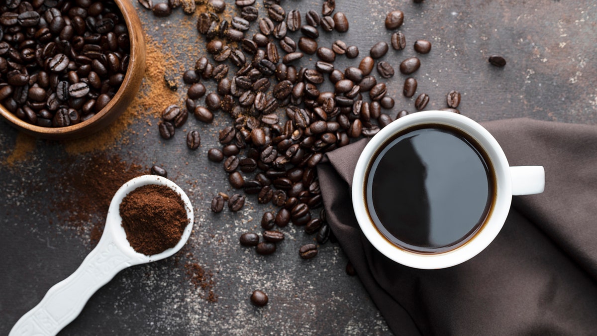 Roasted coffee beans and a cup filled with coffee