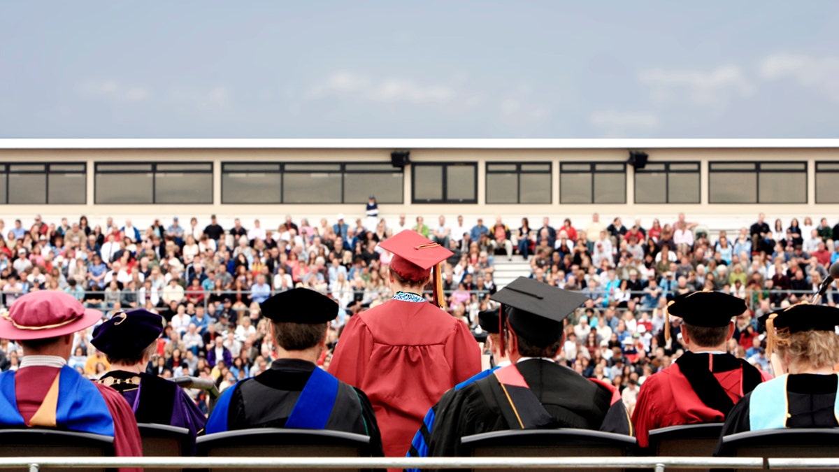 Rear view of valedictorian giving a speech during college graduation ceremony.