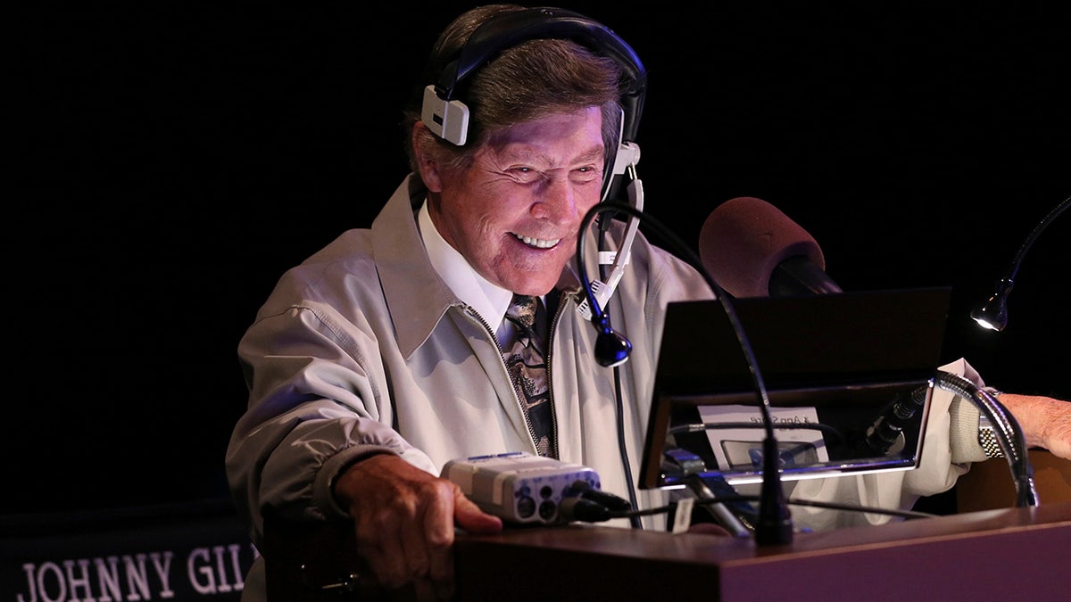 In this image provided by Jeopardy Productions, Inc., show announcer Johnny Gilbert appears on the set of "Jeopardy!" Gilbert worked with host Alex Trebek for 37 years and was reluctant to continue after losing his admired colleague. But others with the show urged him to consider his role as a comforting touchstone for viewers who also were in mourning.