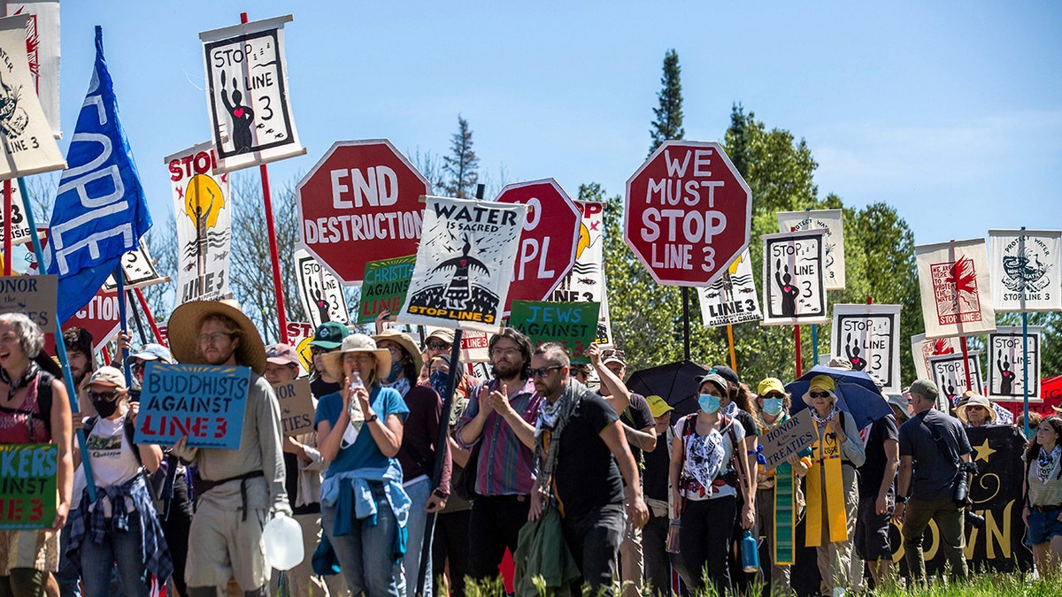 Climate activist and Indigenous community members hold signs during a rally and march in Solway, Minnesota on June 7, 2021. - Line 3 is an oil sands pipeline which runs from Hardisty, Alberta, Canada to Superior, Wisconsin in the United States.