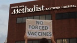 People bring signs to protest Houston Methodist Hospital system's rule of firing any employee who is not immunized by Monday, June 7, 2021, at Houston Methodist Baytown Hospital in Baytown, Texas. Houston Methodist staff who have refused the COVID-19 vaccine so far and their supporters participated in a gathering and march. (Yi-Chin Lee/Houston Chronicle via AP)
