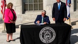 Missouri Gov. Mike Parson signs legislation limiting the during of local public health orders during a ceremony Tuesday, June 15, 2021, outside the state Capitol in Jefferson City, Mo. The new law took effect immediately and was passed in response to local restrictions imposed during the coronavirus pandemic. Among its supporters were state Sen. Sandy Crawford, left, and House Speaker Pro Tem John Wiemann. (AP Photo/David A. Lieb)