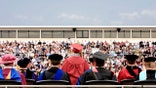 Rear view of valedictorian giving a speech during college graduation ceremony.