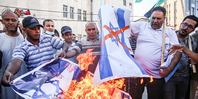 Protesters burn a portrait of Israeli Prime Minister Naftali Bennett and the Israeli flag during a demonstration in the southern Gaza Strip. (Yousef Masoud/SOPA Images/Sipa USA)
