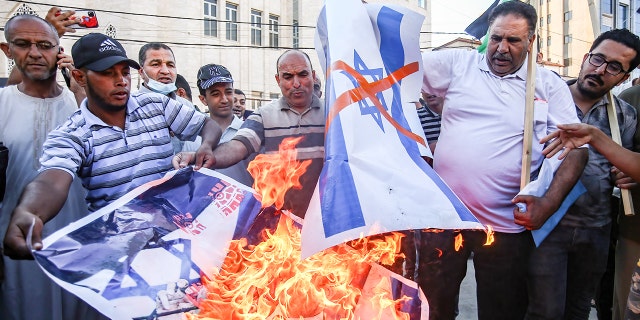 Protesters burn a portrait of Israeli Prime Minister Naftali Bennett and the Israeli flag during a demonstration in the southern Gaza Strip. (Yousef Masoud/SOPA Images/Sipa USA)