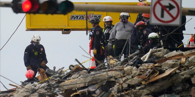 A dog working with search and rescue personnel barks to alert them after sniffing a spot atop the rubble at the Champlain Towers South condo building on Wednesday. (AP)