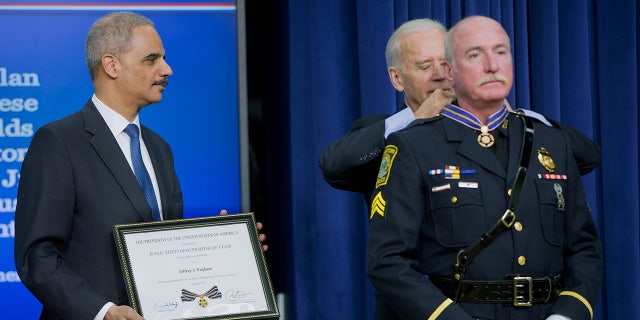 FILE - In this Feb. 11, 2015, file photo, Attorney General Eric Holder and Vice President Joe Biden award the Medal of Valor to Sgt. Jeffrey Pugliese from the Watertown, Mass., Police Department, during a ceremony in the Old Executive Office Building at the White House Complex in Washington. Pugliese, a suburban Boston police officer who became a national hero in 2013 when he tackled one of the Boston Marathon bombers, retired from the only job he ever wanted on Monday June 1, 2021, after more than 41 years on the force. (AP Photo/Pablo Martinez Monsivais, File)