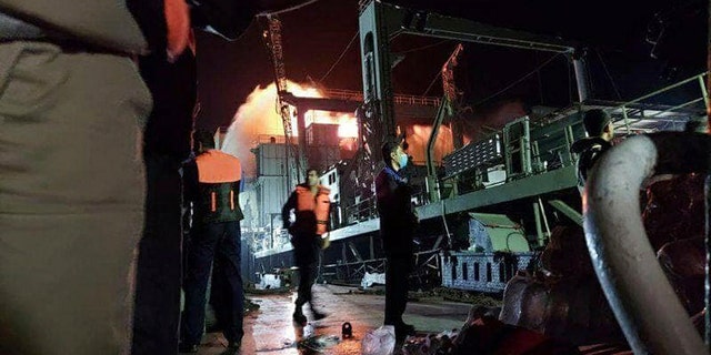 This photo made available by Asriran.com on Wednesday, June 2, 2021, shows personnel standing on Iran's navy support ship Kharg after being caught on fire in the Gulf of Oman. (Asriran.com via AP)