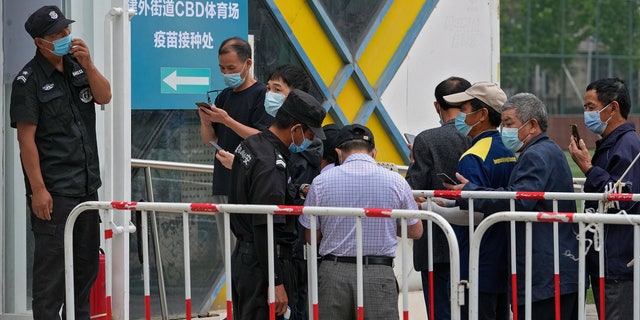 Security guards help masked residents to scan their health code as they line up to receive the Sinopharm COVID-19 vaccine at a vaccination center in the Central Business District in Beijing, Wednesday, June 2, 2021. After a slow start, China is now doing what virtually no other country in the world can: harnessing the power and all-encompassing reach of its one-party system and a maturing domestic vaccine industry to administer shots at a staggering pace. (AP Photo/Andy Wong)