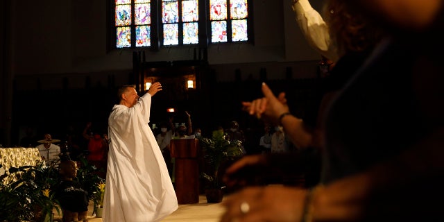 Parishioners raise their hands as Rev. Michael Pfleger conducts his first Sunday church service as a senior pastor at St. Sabina Catholic Church following his reinstatement by Archdiocese of Chicago after decades-old sexual abuse allegations against minors, 일요일, 유월 6, 2021, in the Auburn Gresham neighborhood in Chicago. (AP Photo/Shafkat Anowar)