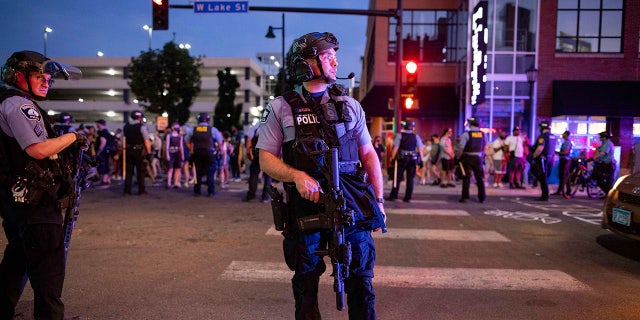 A police officer holds a firearm as community members gather, 일요일, 유월 6, 2021, in Minneapolis, for Winston Boogie Smith Jr., who was fatally shot by members of a U.S. Marshals task force several days earlier. The Minneapolis Police Department forbids its officers from serving on task forces that do not permit them to wear their body cameras, 여우 9 Minneapolis reported. (AP Photo/Christian Monterrosa)