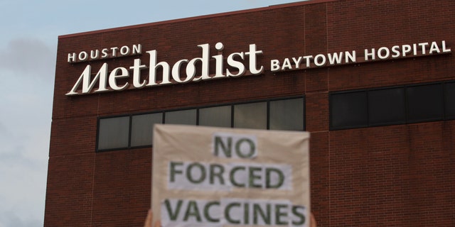 People bring signs to protest Houston Methodist Hospital system's rule of firing any employee who is not immunized by Monday, June 7, 2021, at Houston Methodist Baytown Hospital in Baytown, Texas. Houston Methodist staff who have refused the COVID-19 vaccine so far and their supporters participated in a gathering and march. (Yi-Chin Lee/Houston Chronicle via AP)