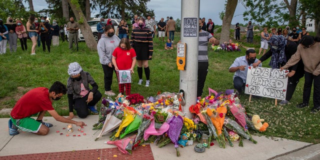 People attend a memorial at the site where a family of five was hit by a driver in London, Ontario, on Monday, June 7, 2021.