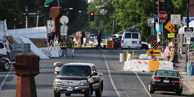 The vehicle travels on Chicago Ave. S. Near E. 38th St. at George Floyd Square, Tuesday, June 8, 2021, in Minneapolis, after city crews returned to GFS to remove debris and barriers for the second time in an attempt to open the intersection to traffic. (David Jolles / Star Tribune via AP)