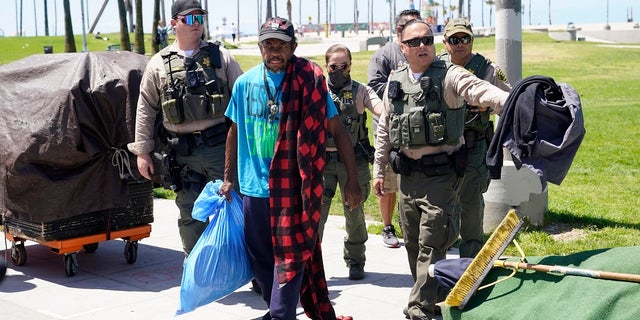 Members of the Los Angeles County Sheriff's Department's HOST, Homeless Outreach Service Team, walk with a homeless man on Tuesday in the Venice Beach section of Los Angeles. (AP Photo/Marcio Jose Sanchez)