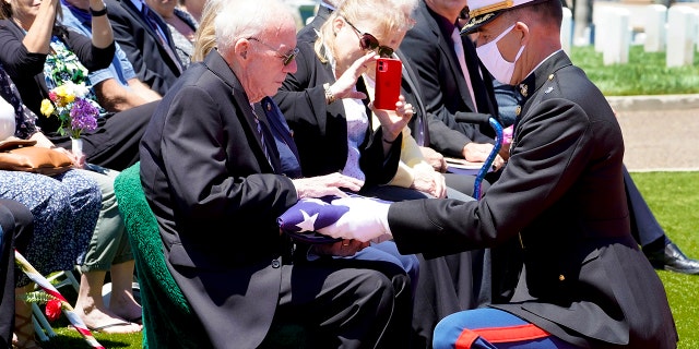 Lt. Col. Christopher Benson, right, presents the flag that covered U.S. Marine Corps, Pfc. John Franklin Middleswart casket, to his nephew Edward Brown during the full military honors ceremony at Fort Rosecrans National Cemetery Tuesday, June 8, 2021, in San Diego. Middleswart was 19 when he was killed along with more than 400 other Marines and Navy sailors aboard the battleship Oklahoma in a surprise attack by the Japanese that led the U.S. into World War II. (Nelvin C. Cepeda/The San Diego Union-Tribune via AP)