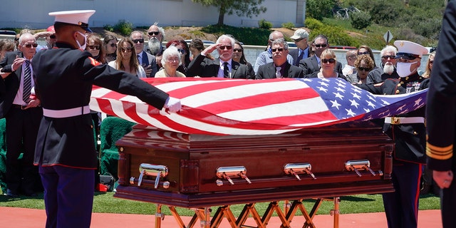 A military honor guard drapes a U.S. flag over the casket of Marine Corps Pfc. John Franklin Middleswart at Fort Rosecrans National Cemetery,  June 8, 2021, in San Diego. Middleswart was laid to rest 80 years after he died in the attack on Pearl Harbor and just months after his remains were finally identified. (Nelvin C. Cepeda/The San Diego Union-Tribune via AP)