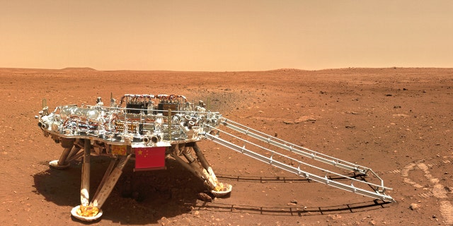 In this image released by the China National Space Administration (CNSA) on Friday, June 11, 2021, the landing platform with a Chinese national flag and outlines of the mascots for the 2022 Beijing Winter Olympics and Paralympics on Mars is seen from the rover Zhurong. China on Friday released a series of photos taken by its Zhurong rover on the surface of Mars, including one of the rover itself taken by a remote camera. (CNSA via AP)