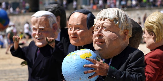 Protestors wearing giant heads portraying G7 leaders participate in a demonstration on a beach outside the G7 meeting in St. Ives, Cornwall, England, Sunday, June 13, 2021. Leaders of the G7 wrap up three days of meetings in Carbis Bay Sunday, in which they discussed such topics as COVID-19, climate, foreign policy and the economy. Leaders portrayed from left, U.S. President Joe Biden, Japan's Prime Minister Yoshihide Suga, British Prime Minister Boris Johnson and German Chancellor Angela Merkel. (AP Photo/Jon Super)