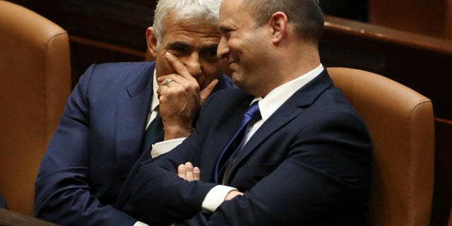 Israel's new prime minister, Naftali Bennett, sits with Yair Lapid, left, during a Knesset session in Jerusalem Sunday, June 13, 2021. Israel's parliament has voted in favor of a new coalition government, formally ending Prime Minister Benjamin Netanyahu's historic 12-year rule. (AP Photo/Ariel Schalit)