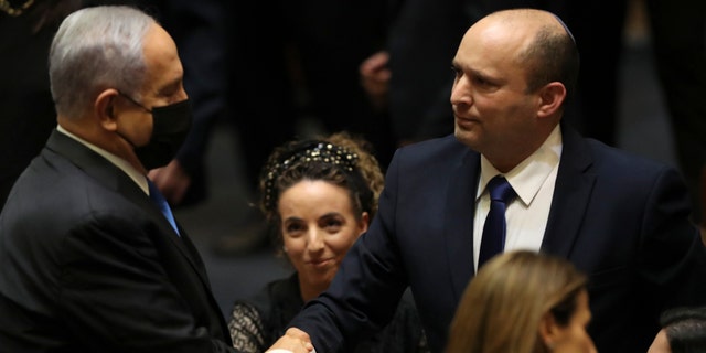 Israel's new prime minister, Naftali Bennett, shakes hands with outgoing prime minister Benjamin Netanyahu during a Knesset session in Jerusalem Sunday, June 13, 2021. Israel's parliament has voted in favor of a new coalition government, formally ending Netanyahu's historic 12-year rule. (AP Photo/Ariel Schalit)
