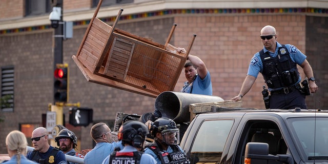 Police remove items used to barricade Lake Street in the Uptown neighborhood of Minneapolis, Wednesday, June 16, 2021. A St. Paul man is accused of speeding and driving into a group of protesters in Minneapolis, killing him One man was charged Wednesday with second-degree murder. 
