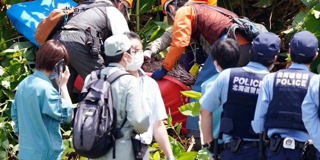 A bear shot dead is carried in Sapporo, northern Japan on Friday. The wild brown bear on the loose all night in the city wounded four people, entered a military camp and disrupted flights at the airport Friday before being shot and killed by authorities. (Yohei Fukai/Kyodo News via AP)