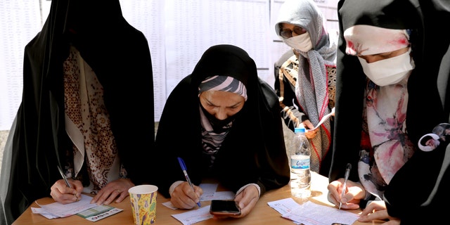 Voters fill out their ballot papers during the presidential election at a polling station in Tehran, Iran, Friday, June 18, 2021. Iranians voted Friday in a presidential election that a hard-line protege of Supreme Leader Ayatollah Ali Khamenei seemed likely to win, leading to low turnout fueled by apathy calls for a boycott. (AP Photo/Ebrahim Noroozi)
